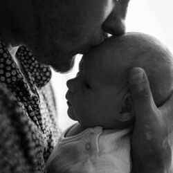 photo d'un papa enbrassant le front de son bébé